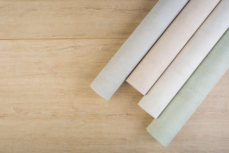 several rolls of multi-colored paper wallpaper on a wooden tableの写真素材