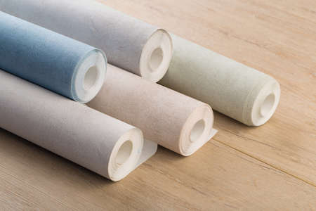 several rolls of multi-colored paper wallpaper on a wooden tableの写真素材