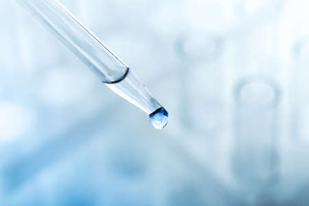 pipette with a drop and scientific laboratory test tubes in a research laboratory. study of a virus...