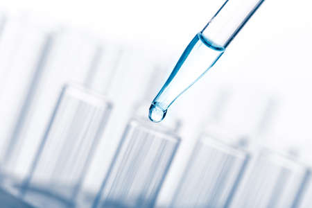 pipette with a drop and scientific laboratory test tubes in a research laboratory. study of a virus...