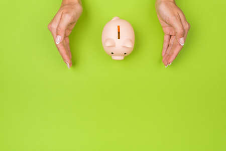 Woman holds piggy bank on a green table