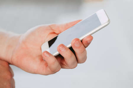 male hands holding a modern phone mock-up for your text message or information content, on a light...