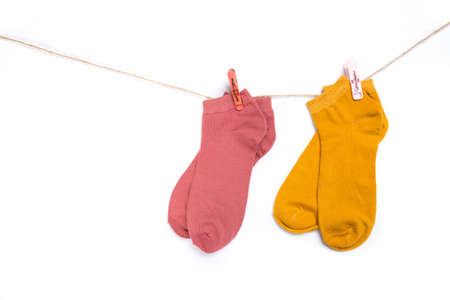 several colored new short socks hanging on a rope with clothespins isolated on white backgroundの写真素材