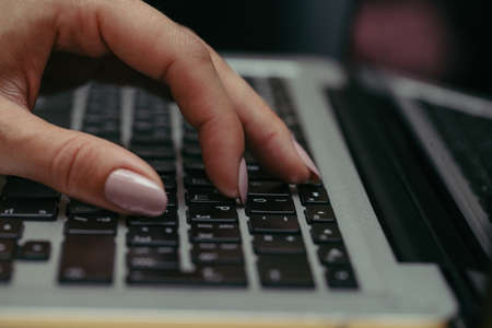 Hands typing on silver laptop computer keyboard, close upの写真素材