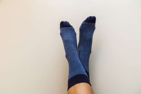 female legs in new blue socks on a light beige backgroundの写真素材