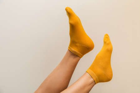 woman legs in new yellow socks on a light beige backgroundの写真素材