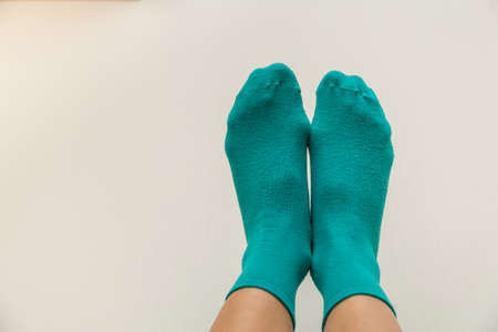 woman legs in bright green socks on a light beige backgroundの写真素材