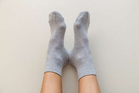 Legs of a young woman in gray socks on a light beige backgroundの写真素材