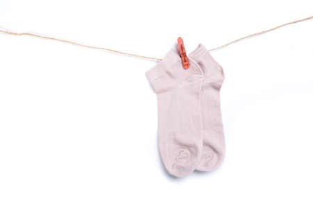 pink sock hanging on a rope with clothespins isolated on white backgroundの写真素材