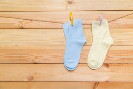multicolored socks hanging on a clothesline with clothespins on a wooden backgroundの写真素材