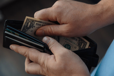 the hands of a working man put one dollar bills in an empty wallet. Poverty concept, crisis. firing...