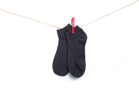 dark gray sock hanging on a rope with clothespins isolated on white backgroundの写真素材