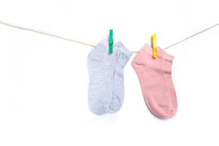 several colored new short socks hanging on a rope with clothespins isolated on white backgroundの写真素材