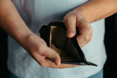 Empty wallet in the hands of a man at home. Poverty concept, crisis. dismissal, no earnings