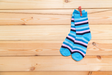 multicolored socks hanging on a clothesline with clothespins on a wooden backgroundの写真素材