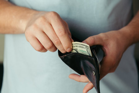 the hands of the bankrupt man take the last dollar bills from the empty wallet. Poverty concept, crisis. dismissal or cost savingsの写真素材