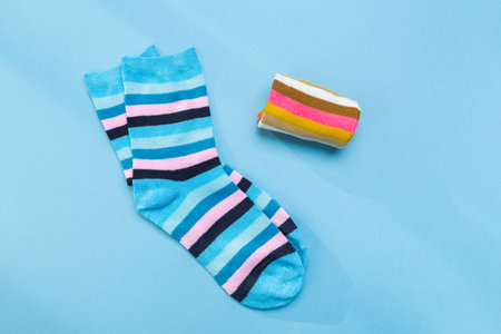 two pairs of multicolored new socks stacked on a blue background. top view. place for text.の写真素材