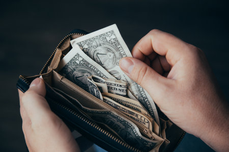 man shows wallet with a bundle of dollar bills, there is little money in the wallet, financial...