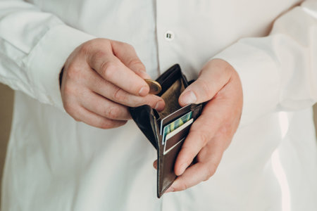 wallet in the hands of a bankrupt man. hand puts one coin. Poverty concept, crisis. dismissal or...