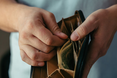 wallet with various dollar bills in the hands of a bankrupt man. Reduced costs, low salary