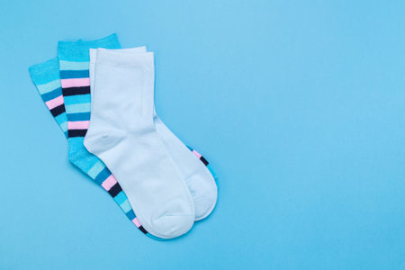 two pairs of multicolored new socks stacked on a blue background. top view. place for text.の写真素材