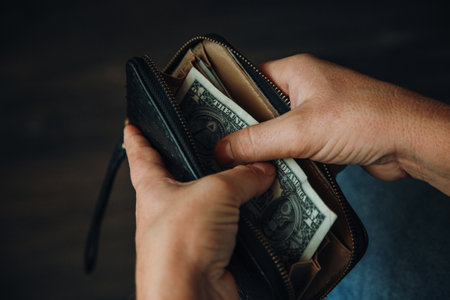 man shows wallet with a bundle of dollar bills, there is little money in the wallet, financial...