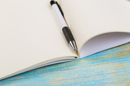 school colored notepads with ballpoint pen on blue wooden background