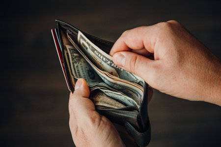 man shows wallet with a bundle of dollar bills, there is little money in the wallet, financial...