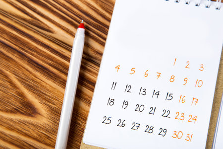 white calendar for 2021 month schedule to make an appointment or manage the schedule every day on a wooden table with a ballpoint pen for marks, for work planning and life conceptの写真素材