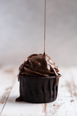 cupcakes with coffee cream poured with chocolate on a light background. delicious dessert, close-upの写真素材