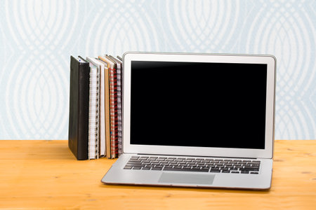 Notebook with multi-colored books on a wooden table. mockup for text. distance learning conceptの写真素材