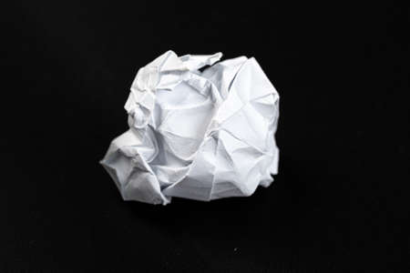 A piece of crumpled white paper on a black background.の写真素材