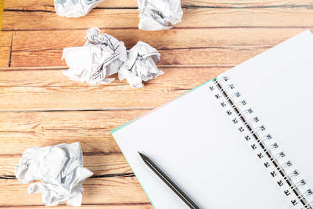 Writing concept - crumpled up paper wads with a sheet of white paper and pencilの写真素材