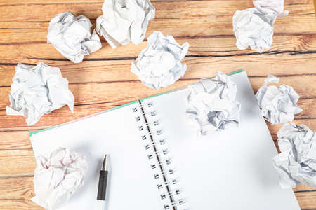 Writing concept - crumpled up paper wads with a sheet of white paper and pencilの写真素材