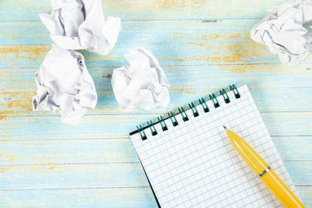 Writing concept - crumpled up paper wads with a sheet of white paper and pencilの写真素材
