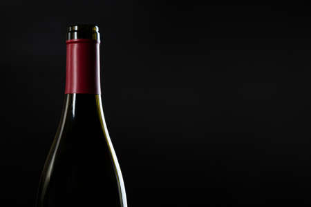 one open bottle of wine on a dark glossy background.の写真素材