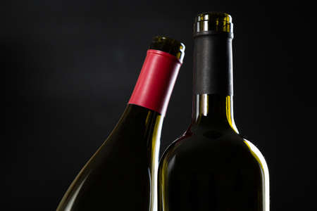 two open empty bottles of wine on a dark glossy background.の写真素材