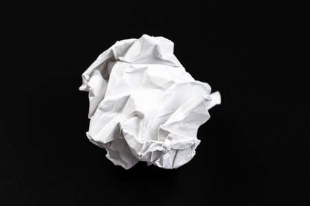 A piece of crumpled white paper on a black background.
