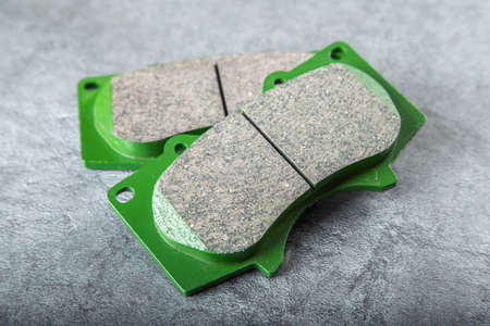A set of four new car brake pads on a gray background.
