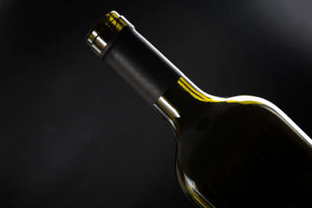 one open bottle of wine on a dark glossy background.の写真素材