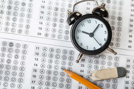 answer sheet, test in exercise and passing examination paper computer sheet with pencil alarm clock and pencil for education conceptの写真素材