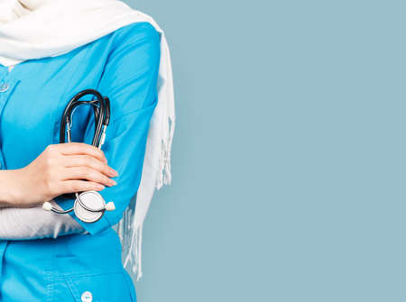 Portrait of a friendly, muslim doctor or nurse woman in hijab with a stethoscope on a blue background. health workerの写真素材