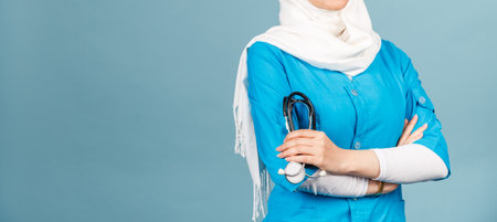 Portrait of a friendly, muslim doctor or nurse woman in hijab with a stethoscope on a blue background. health workerの写真素材