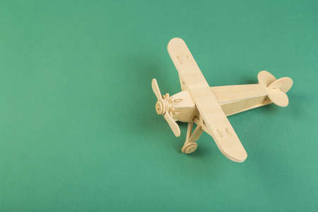 Model of a wooden toy plane, airliner, on a green background. the concept of travelの写真素材