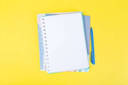 open spiral notepad on a yellow background with a pen. top view, stack of notepad with blank sheet. school concept, businessman work desk.の写真素材