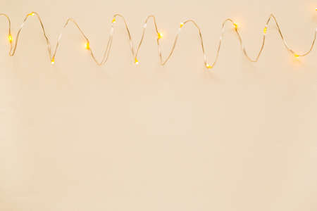 The garland is on. Glowing electric garland on an abstract light beige background. view top place...