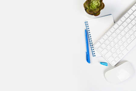 White office desk with blank laptop, computer keyboard and other stationery, potted plant. Top view...