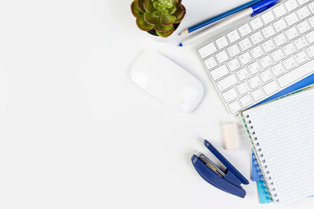 White office desk with blank laptop, computer keyboard and other stationery, potted plant. Top view...