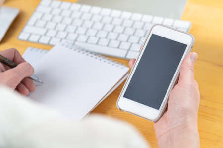 woman hands close up working on white computer keyboard and smartphone, work from home concept. work online, shoppingの写真素材