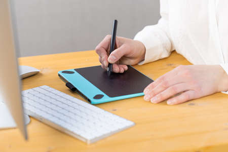 Hand of graphic designer working with stilus and tablet